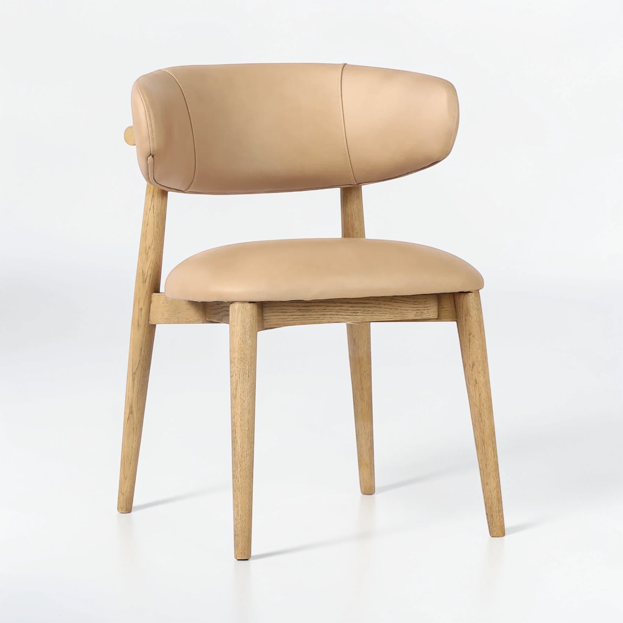 SWANK Muebles + Decor Tavo chair with light tan leather upholstery and natural wood legs. Contemporary dining chair with curved back.